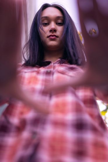 Low-angle portrait of a woman looking down with hands framing the shot.