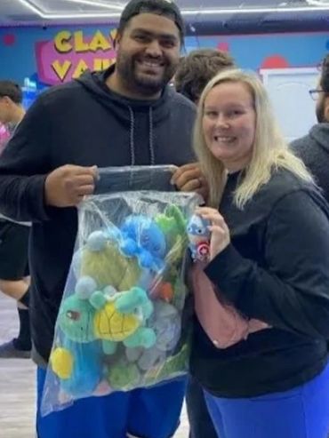 A young couple holding a bag of plushie wins.