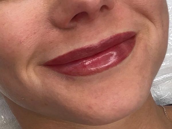 Close-up of lips with shiny dark red lipstick.