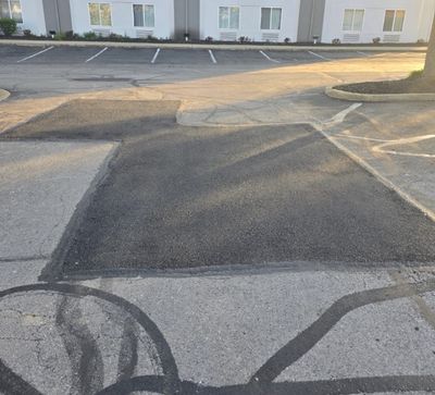Freshly patched asphalt area in a parking lot at sunset.