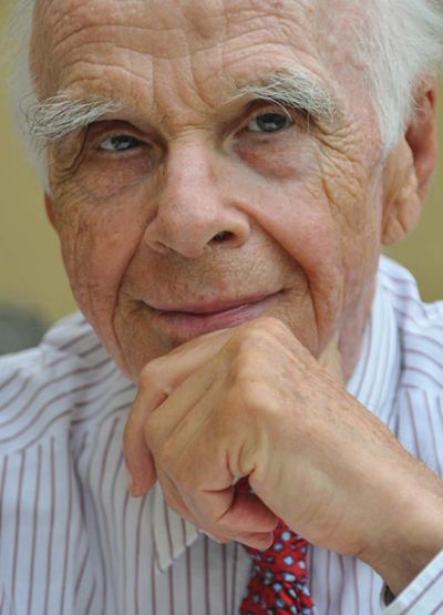 Portrait of Ervin Laszlo with white hair and a thoughtful expression.
