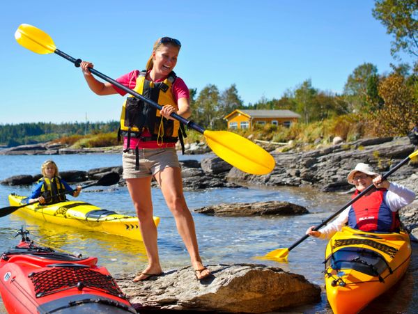 Female kayak instructor teaching two women in sea kayaks how to use a paddle.