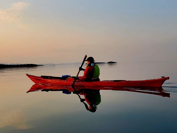 A sea kayaker paddling on a calm ocean day.