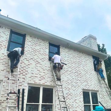 Crew on ladders  replacing windows on a house