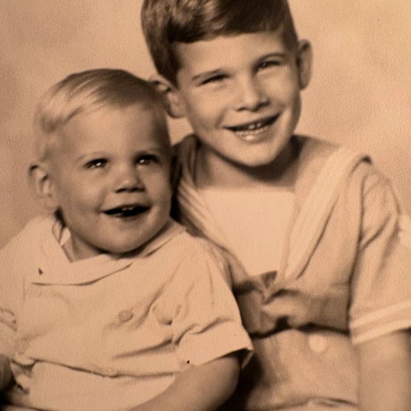 Two smiling brothers in vintage clothing.