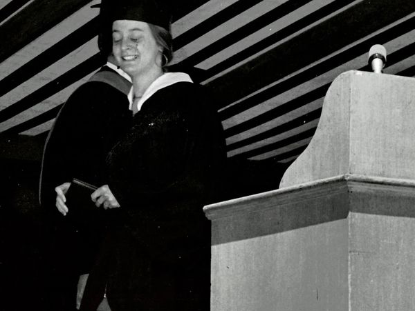 Graduate smiling and hugging during ceremony.