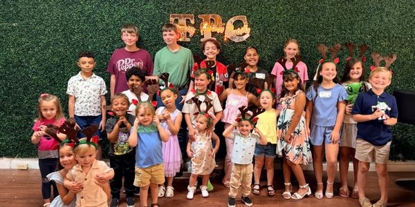 Group of children posing in front of a green wall.