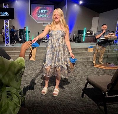 Young woman handing out items in a church setting.