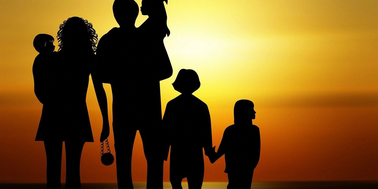 Silhouette of a family on the beach looking out over a sunset, signifying hope and optimism.