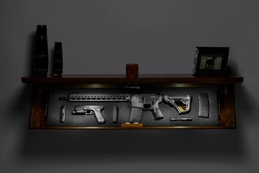 TacticalTrap shelf mounted on the wall open with rifle, pistols, and magazines mounted within it. Se