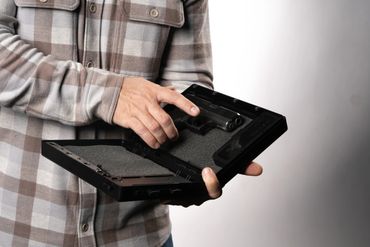 Man holding black StopBox with it open in front of a white wall