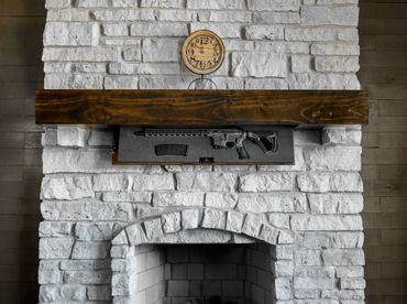 Wood TacticalTrap shelf mounted over a brick fireplace, open with rifle and magazine on display.