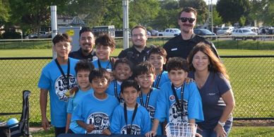 Group photo of a youth soccer team with coaches and police officers.
