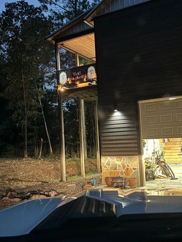 Night view of a wooden house with a balcony sign reading 'Yeti Spaghetti'.