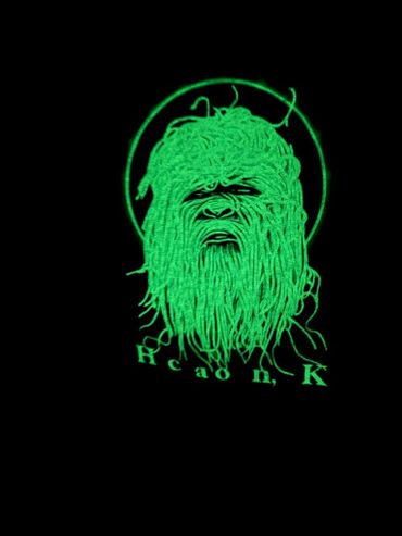 Green neon sketch of a bearded face with the word 'Hcaon,K' below it.