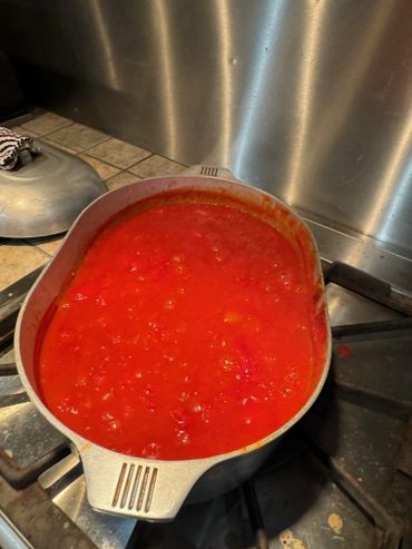 A pot of red tomato sauce simmering on a stove.