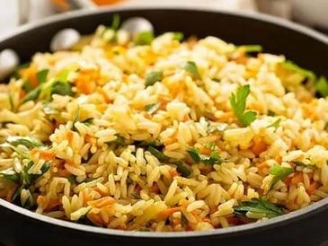 A pan filled with cooked rice mixed with vegetables and herbs.