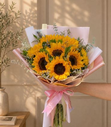 Bouquet vibrante trabajado con girasoles como flor principal, acompañado de follajes ligeros y envol