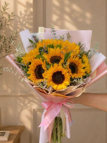 Bouquet vibrante trabajado con girasoles como flor principal, acompañado de follajes ligeros y envol