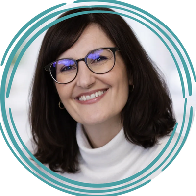 Smiling woman with glasses and dark hair in a white turtleneck.