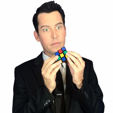 Man in a suit concentrating on solving a Rubik's Cube.
