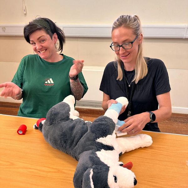 women practising bandaging on stuffed dog