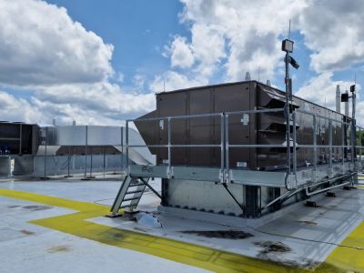 Large HVAC unit on rooftop under cloudy sky.