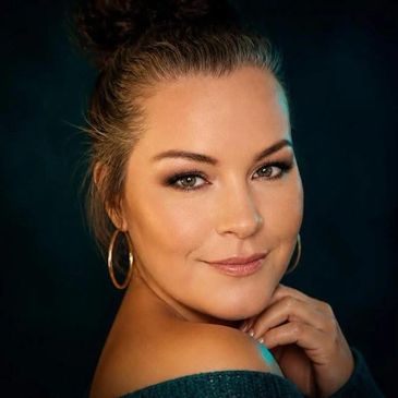 Portrait of a woman with hoop earrings and an off-shoulder top.