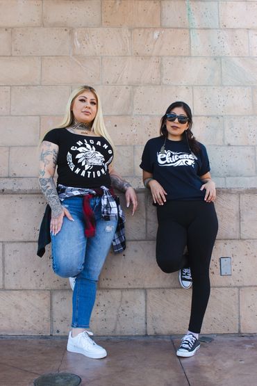 Two woman wearing chicana gear
