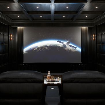 Luxurious black home theater with leather seats and space-themed screen.