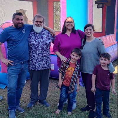 Family portrait in front of a bouncy castle at an outdoor event.