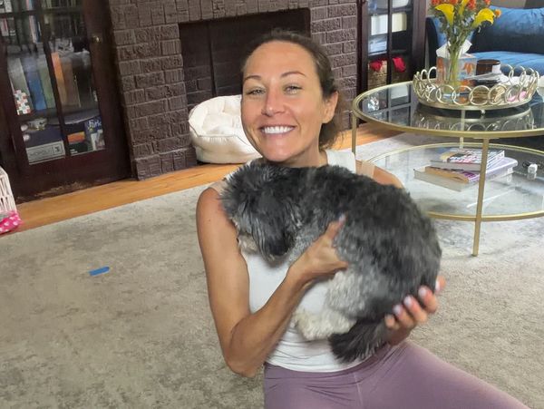 Smiling woman holding a small dog indoors.