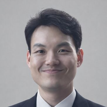 Smiling man in a suit against a plain background.