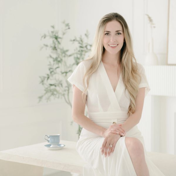 Smiling woman with long blonde hair in a white dress.