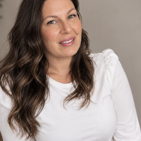 Smiling woman with wavy brown hair in white shirt.