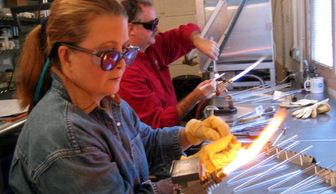 Participants learning Glass Beadmaking at a fundraising event benefitting Children's Hospital.