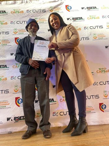 Two people holding a certificate at an event.