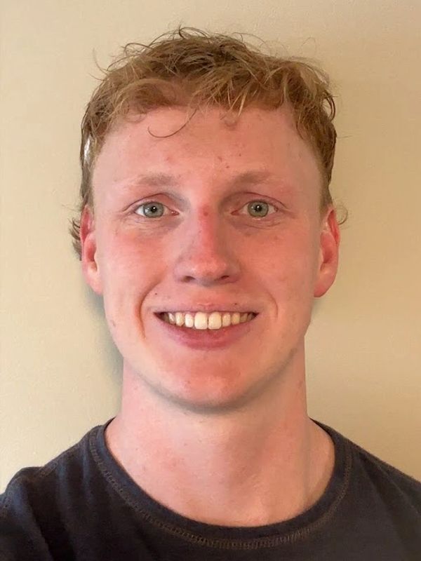 Young man smiling against a plain background.