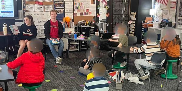 Teacher reading to a group of children in a classroom.