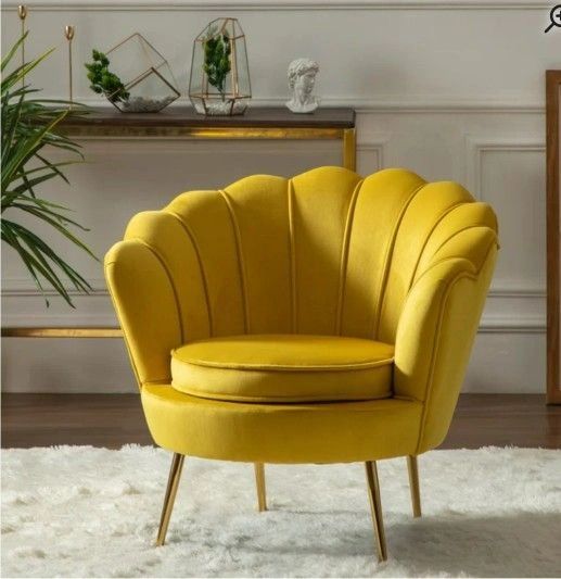 Yellow tufted velvet barrel chair on a white shag rug with tropical and gold decor in the background