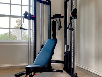 Home gym setup with a versatile weight machine and bench.