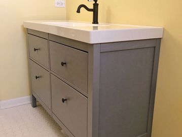 Modern gray bathroom vanity with four drawers and white countertop.