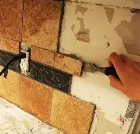 Hand installing decorative tiles on a wall.