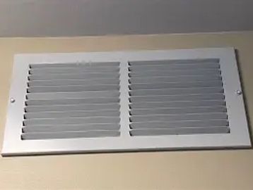 White rectangular air vent on a beige wall.