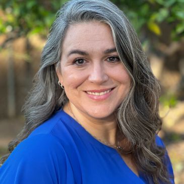 Smiling woman with gray hair wearing a blue top.