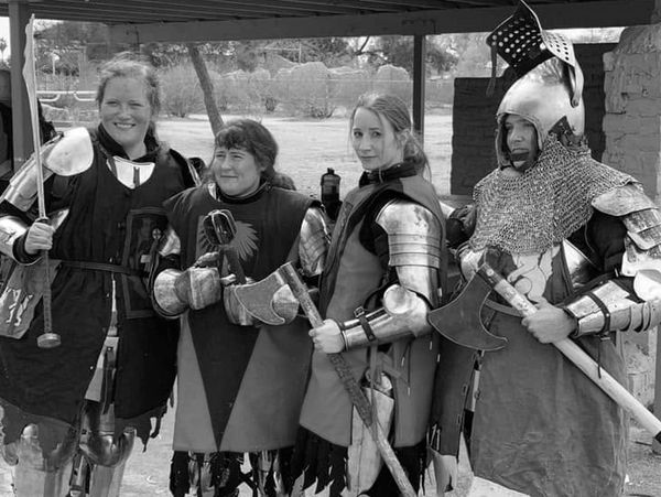 Four women dressed in medieval armor holding weapons.
