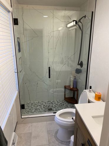 Modern bathroom with glass shower and marble tiles.