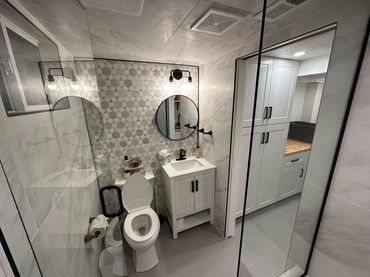 Modern bathroom with patterned tile wall, white vanity, and glass shower enclosure.