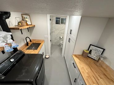 Modern laundry room with black appliances and wooden countertops.