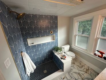 Modern bathroom shower with blue patterned tiles and hexagonal floor tiles.